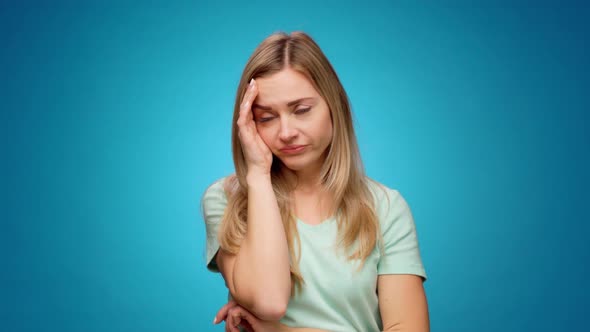 Young Woman Has Headache Standing Against Blue Background
