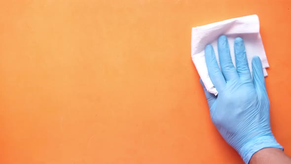 Hand in Blue Rubber Gloves Cleaning Table with Cloth