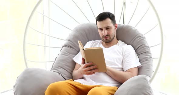 Man reading a book on the sofa at home.