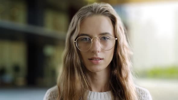 Portrait of Serious Clever Girl in Eyewear Looking at a Camera in a Street Background. A Smart Woman