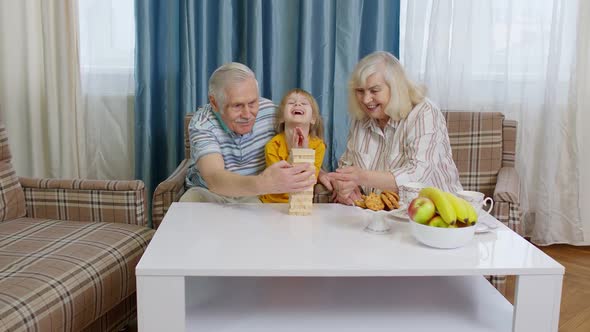 Senior Couple Grandparents with Child Kid Granddaughter Playing Game with Wooden Blocks at Home