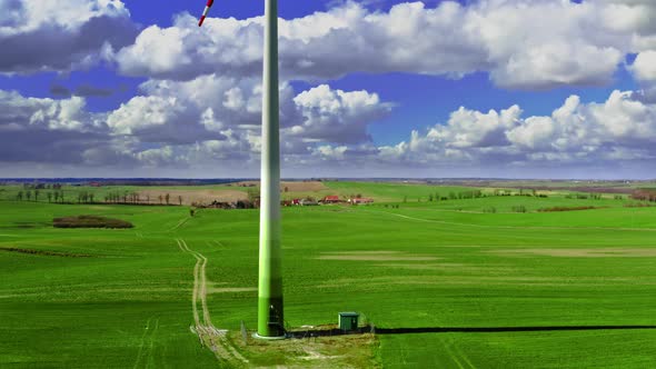 White wind turbine on green field in spring, aerial view