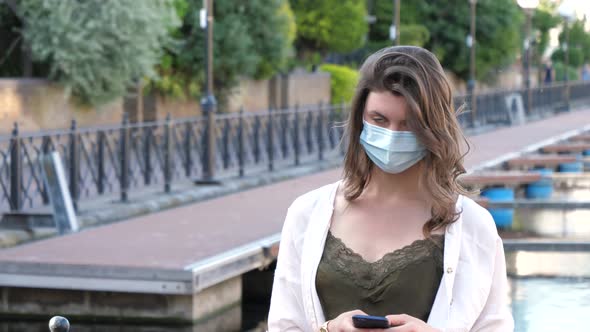 Portrait of brunette woman with protective mask using smartphone