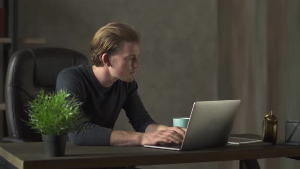 Handsome Businessman Working at Notebook at the Modern Office. A Successful Young Man of Business