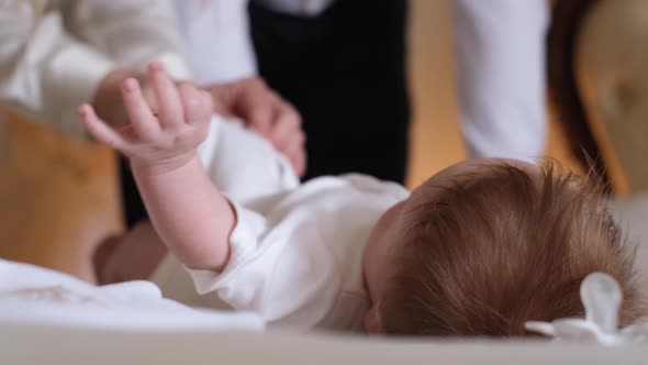 Mom Dresses Her Little Tender Baby in a White Bodysuit