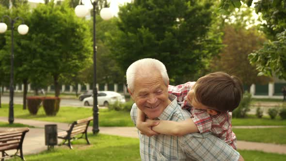 Senior Man Holds His Grandson on His Back