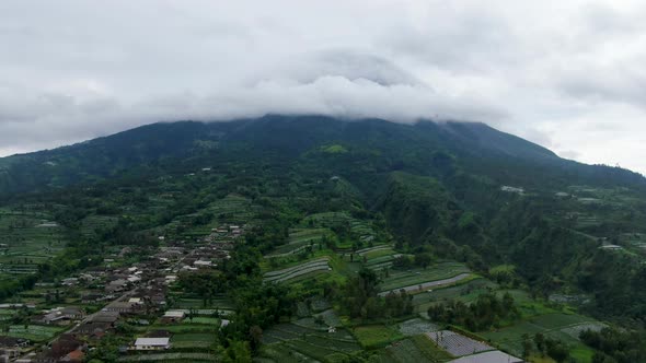 Javanese farmland and summit of Mount Merapi covered with clouds, aerial view