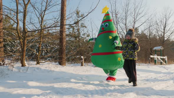 Little Boy Walking with a Man Wearing an Inflatable Christmas Tree Costume