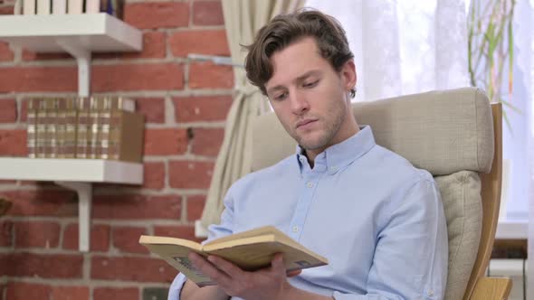 Young Man Reading a Book in Modern Office