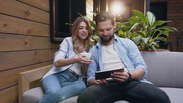 Modern Couple in Love which Using Tablet PC while Sitting on Soft Couch in Hotel Lobby