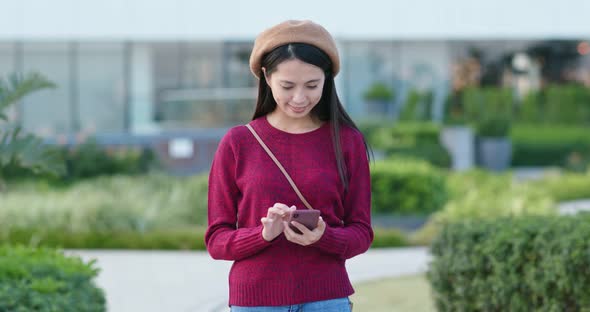 Woman work on mobile phone in city park