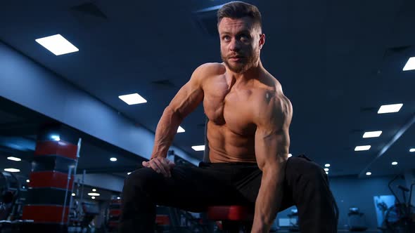 Handsome strong young bodybuilder work out with dumbbells. Strong abs