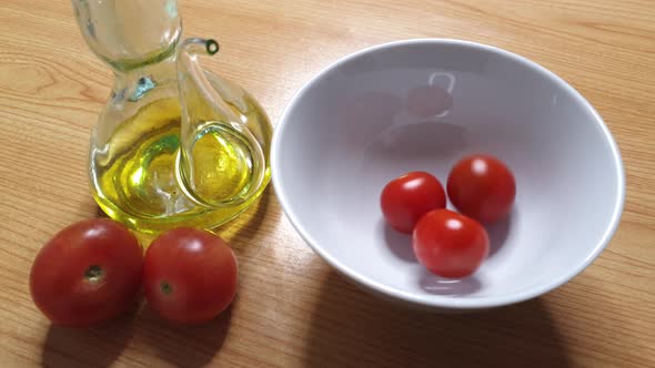 Salad tomatoes falling into white bowl