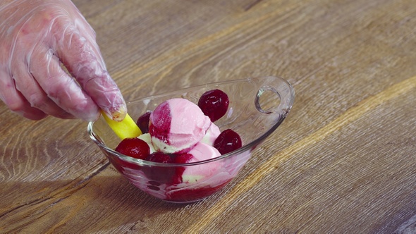 Decorating multicolor ice cream balls with cherry berries, marsh mallow and sweet glaze	