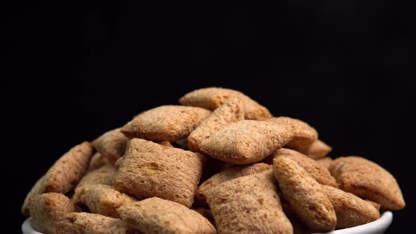 Crispy chocolate pads rotation in macro on black background. Cereal dessert for a fast breakfast