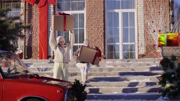 Happy Teen Girl Rising Up Big Gift Box on Countryside Cottage Landscape at New Year Eve. Cheerful