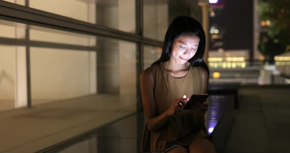 Woman using smart phone in Hong Kong at night 