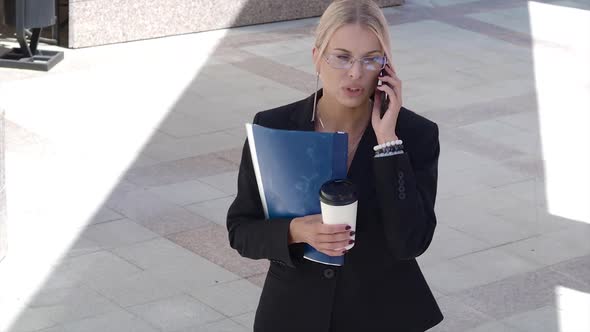 Serious Woman Lawyer Talking Phone While Ealking in the Business District of the City.