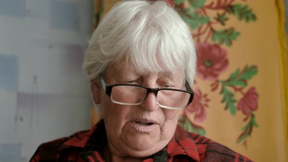 A Closeup View of a Beautiful Mature Woman Wearing Eyeglasses is Reading a Newspaper