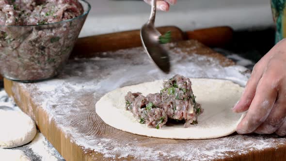 Chef make meat pies kutaba or chebureki, raw minced meat with onions and herbs filling dough.