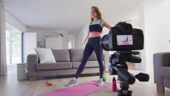 Woman performing exercise at home and recording it with digital camera