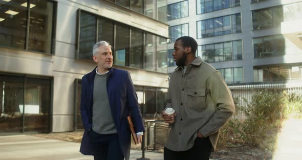 Two Men of Different Ages and Nationalities are Talking Walking in Office Center