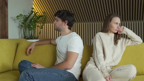 Young Couple Experiencing Relationship Problems Is Sitting Next To Each Other at Home on a Yellow