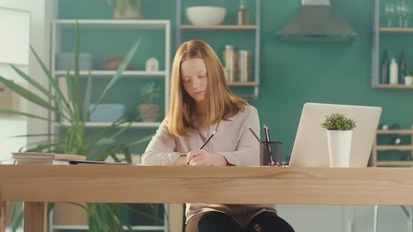 Redhaired Teenage Girl Studying at Home Online Watching a Video Tutorial