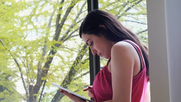 Beautiful woman using digital tablet near window 4k