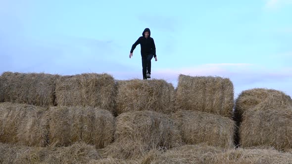 Caucasian Boy on a Farm Field Jumping From a Haystack