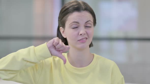 Portrait of Young Woman Showing Thumbs Down Gesture