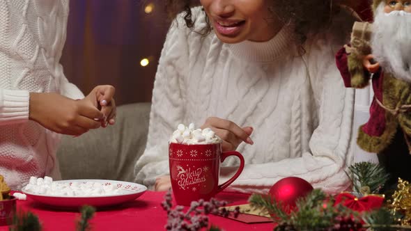 African American Mom and Little Daughter in White Sweaters Garnish a Cup of Hot Drink with Whipped