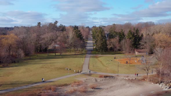 Drone view of a lakeside park with a road vanishing off into the distance, pulling back over the wat