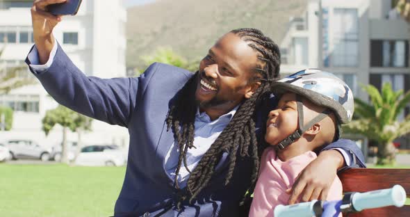 Video of happy african american father and son in helmet taking selfie outdoors