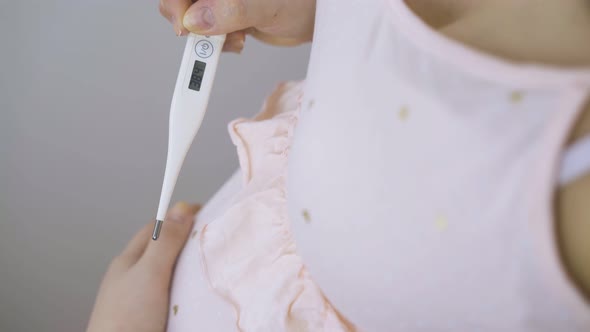 Pregnant Woman Holds Digital Thermometer Stroking Tummy