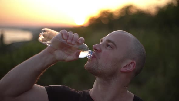 Closeup Slow Motion Side View of Caucasian Bald Muscular Guy Wearing Black Tshirt Drinking Water