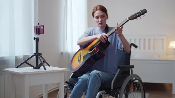 A Young Disabled Lady is Telling About the Guitar and Preparing to Play