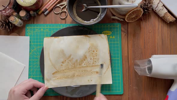 Artist's Hands Decorate Craft Paper in Dish with Water and Coffee