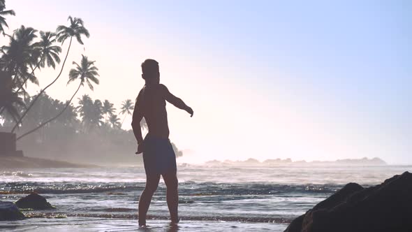 Muscular Athlete Silhouette Exercises on Sandy Beach