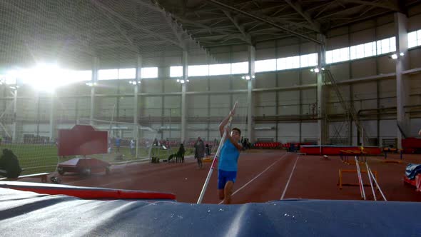 Pole Vaulting - Young Sportsman in Blue t Shirt Is Running and Jumping Over the Bar