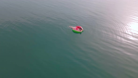 Overhead Top View of Woman Swimming with Watermelon Swimming Circle in Blue Water