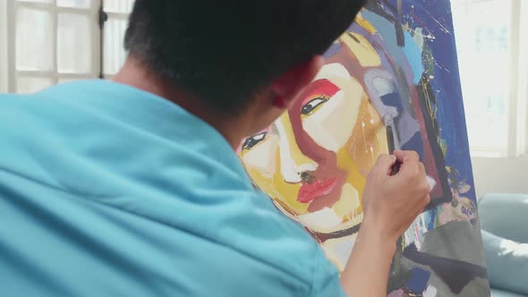 Close Up Hind View Of An Asian Artist Man In Wheelchair Holding Paintbrush Painting A Girl's Face