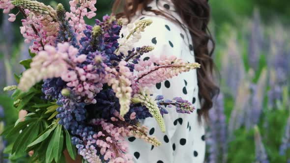 Young Beautiful Woman Posing in a Field with a Bouquet of Lilac Flowers. Happy Brunette in a Field