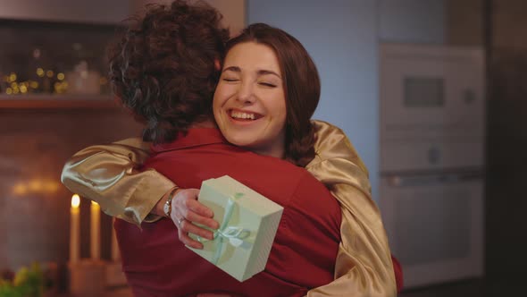 Happy Woman Hugging Man with Gift Box in Hands