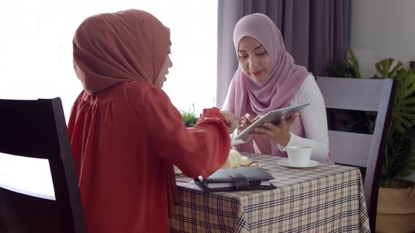 Young muslim working woman discussing with friend in coffee shop