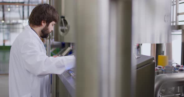 A Male Brewer with a Beard at Brewery Factory Working Behind the Control Panel Dashboard