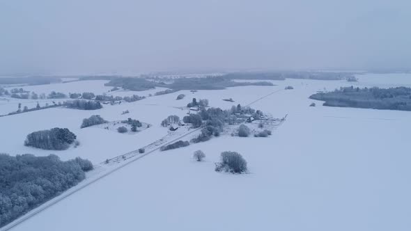 Aerial view of snowy forests and farmlands in Estonia.