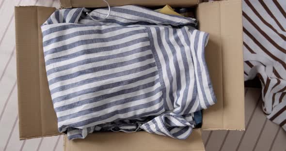 Bunch of clothes being packed in box, donation concept.
