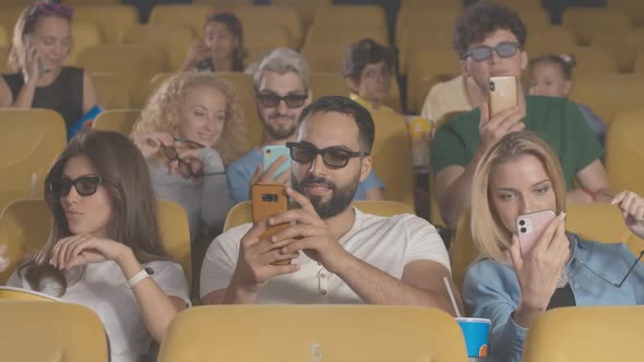 Group of Film-loves Using Smartphones Before Film in 3d Cinema. Portrait of Relaxed Multiethnic Men