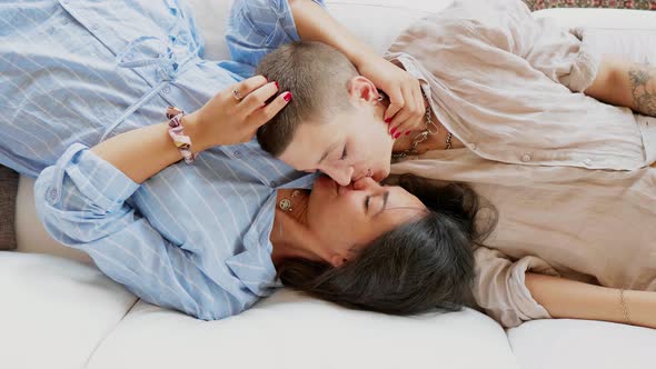 Affectionate lesbian couple kissing and talking on sofa
